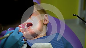 The dentist treats the teeth of a frightened redheaded boy