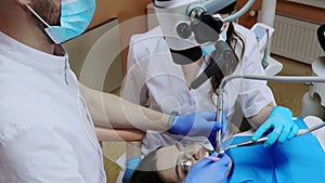 A dentist treats a woman's teeth using a cofferdam. Dental equipment