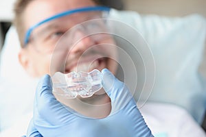 Dentist tries on silicone mouthguard to patient