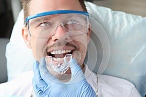 Dentist trying on mouthguard for man patient