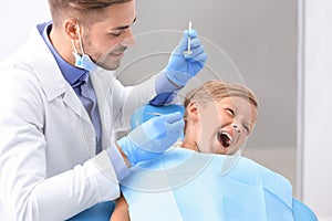 Dentist trying to examine teeth of naughty little boy in clinic