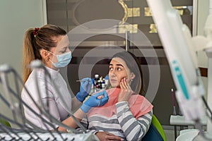 Dentist in uniform consults a young woman in the dental office. Dental procedure