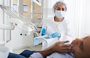 Dentist in uniform is examinating man on chair