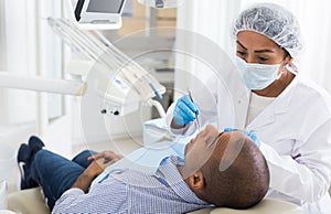 Dentist in uniform is examinating man on chair