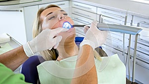 Dentist using dental curing UV light lamp for treatment