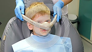 Dentist using nitrous oxide in dental clinic while treating young patients with milk teeth. Relaxation of patient before