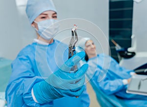 Dentist using surgical pliers to remove a decaying tooth.