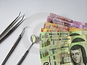 dentist utensils for oral review and mexican banknotes