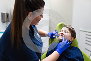 Dentist visually assesses the condition of the teenager`s teeth. Boy at the dentist.