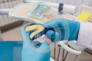 Dentist wearing protective gloves squeezes out the mass into the articulator with teeth mould