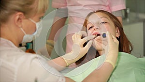 Dentist who keeps a syringe in his hands sprinkles a firming liquid on his teeth