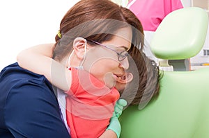 Dentist woman hugging child patient