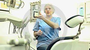 Dentist woman near dental chair, welcoming patient to office