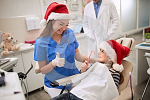 Dentist woman in Santa hat examining tooth patient in ambulant