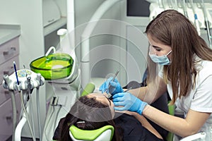 Dentist at work examining woman`s teeth