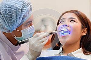 Dentist working on dental curing with UV light equipment for patient's teeth