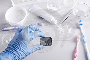 Dentist workplace.Doctor holding dental x-ray, toothbrush,toothpaste and medical equipment on the white table