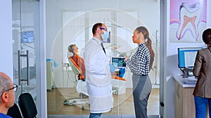 Dentistry doctor showing x-ray of teeth to patient using tablet