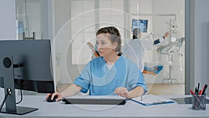 Dentistry nurse sitting at desk typing on computer keyboard