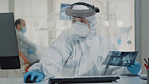 Dentistry specialist holding x ray while using computer