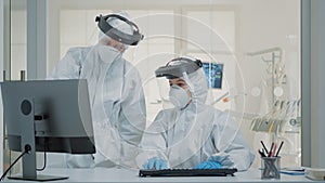 Dentistry team of specialists with ppe suits using computer