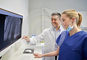 Dentists with x-ray on monitor at dental clinic