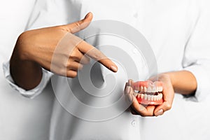 Denture in the hands of the dentist. The doctor is holding a denture. Dentistry is a Conceptual photo. Prosthetic dentistry. False