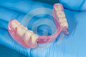 Denture. Partial removable denture of the lower jaw of a person with white beautiful teeth in the hand of a dentist. Aesthetic