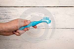 Denture toothbrush in hand. Effective cleaning of teeth and gums