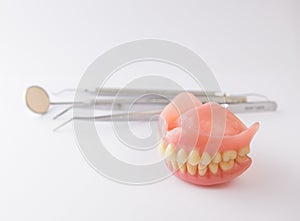 Dentures and dental tools on white background