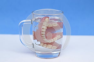 Dentures in a glass glass with water. Use of dentures, problems with teeth