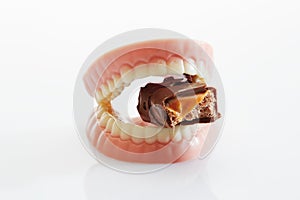 Dentures made of sugar and white chocolate biting chocolate bar
