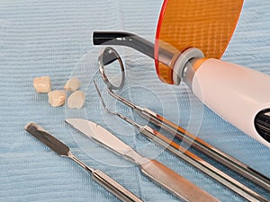 Dentures and metal dental instruments lying on blue sterile napkin