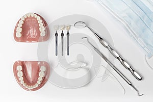 Dentures next to floss and metal pick and mirror