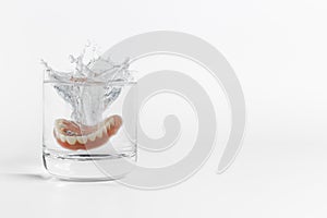 Dentures splashing in glass of water