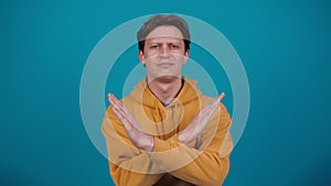 Denying, rejecting, disagree. Dissatisfied man disapproving, making negation gesture. Portrait of young guy on blue