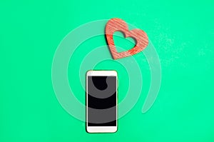 Dependence on social networks. phone smartphone and heart on a green background. online dating, flirting, message and calling your