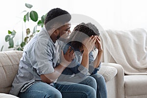 Dependent Relationship. Young Black Guy Soothing His Depressed Girlfriend At Home photo