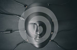Depersonalized human robot android face connected with many digital device wires cables chargers. Digitalization, chipization,