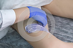 Depilation With Hot Wax Woman`s Leg In Spa. Closeup of Body Hair removal During Hair removal Process on Caucasian Female Leg with