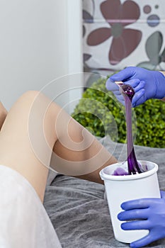 Depilation Spa Procedure. Female Legs Being Covered With Liquid Purple Wax Composite During Waxing or Sugaring Proceedure in