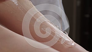 Depilatory gel being applied on woman`s legs by stick