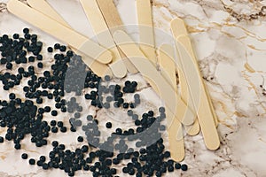 depilatory pearly blue solid wax beans and wooden stick on marble background