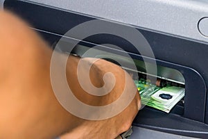 Depositor withdraws EURO from ATM cash money machine. Man hand holding EURO banknotes at the ATM machine photo