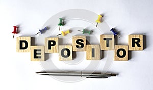 DEPOSITOR - word on wooden cubes with stationery buttons, pen on white background photo