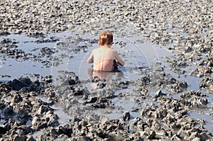 Deposits of natural healing clay. The child gladly accepts mud b