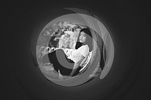 A depress asian young girl hildding in big concrete water pipe in white tone