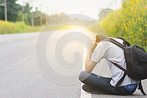 depress and hopeless , Travel hitchhiker man with backpack sitting on roadside, waiting for car