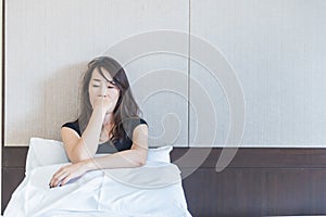 depress woman sitting on bed in room with hand on her mouth,