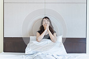 depress woman sitting on bed in room with hand on her mouth